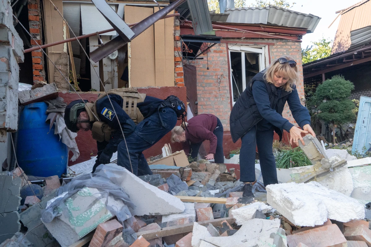 People clear debris from a residential building damaged by a Russian airstrike in Ukraine.